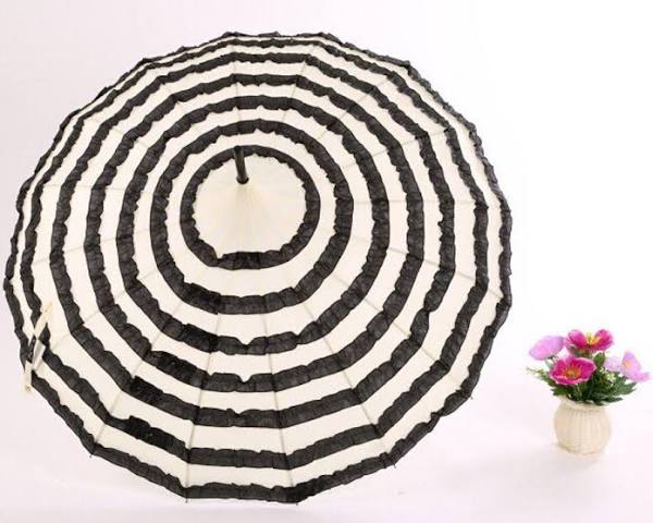 Black and white striped umbrella on a white background with a small plant.